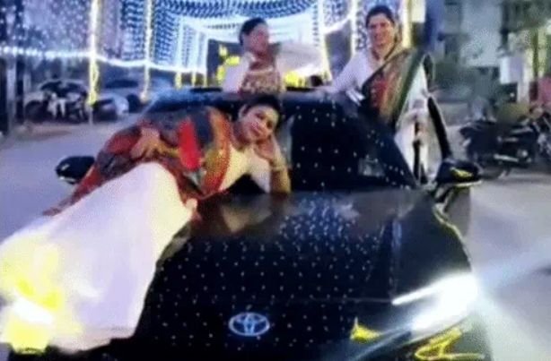 Dangerous stunt by 3 young women on a moving car! One lay on the bonnet, while others danced while hanging onto the doors.